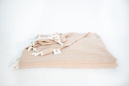 An oversized desert stone cotton throw blanket folded with the Vervain Threads label displayed.