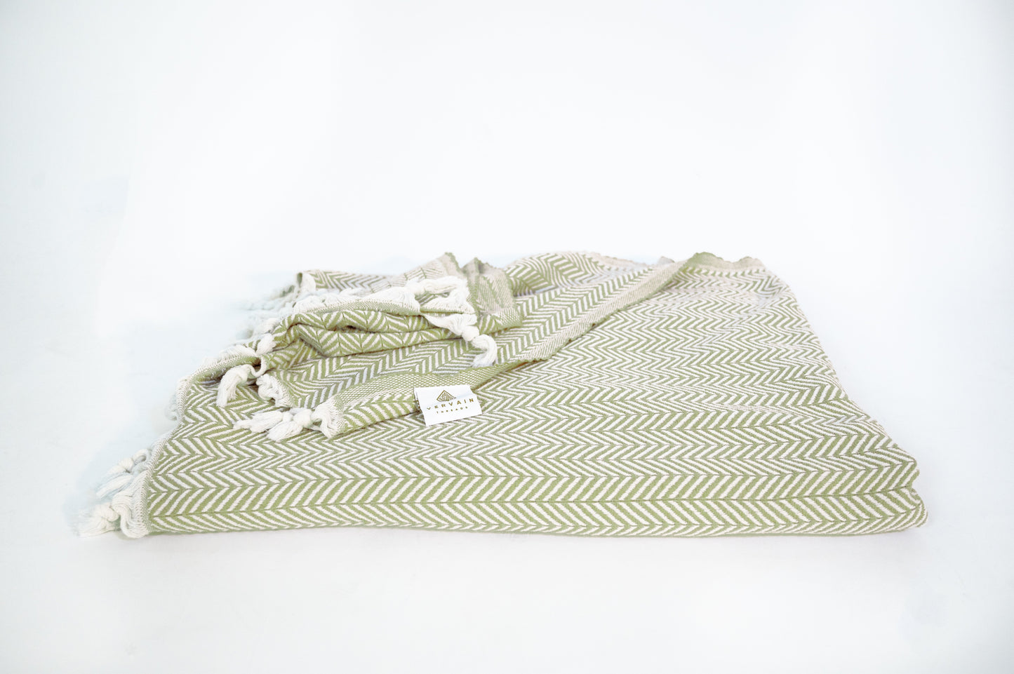 An image of the palmetto green blanket folded up with the Vervain Threads label showing. 