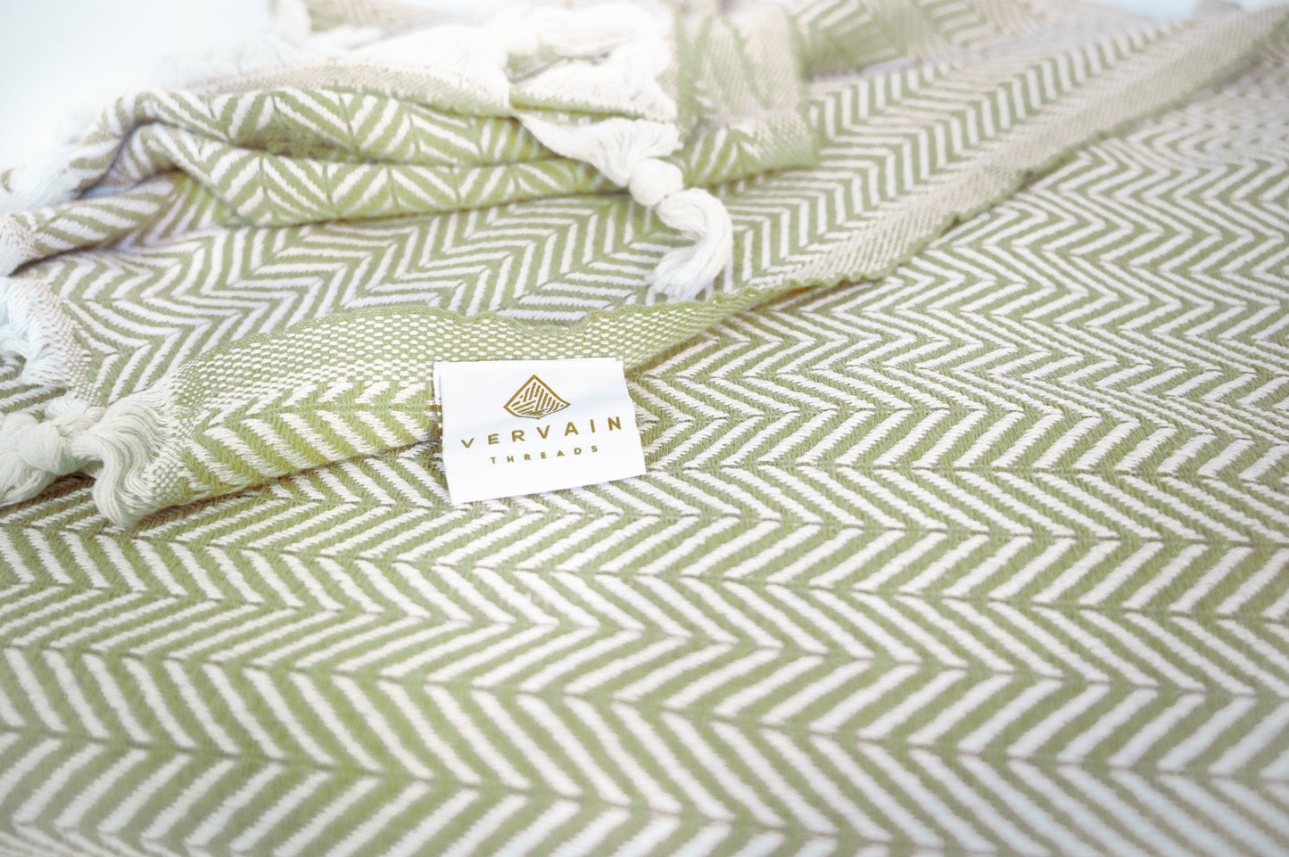 A close up shot of the palmetto green herringbone throw blanket with the detailed weave visible.