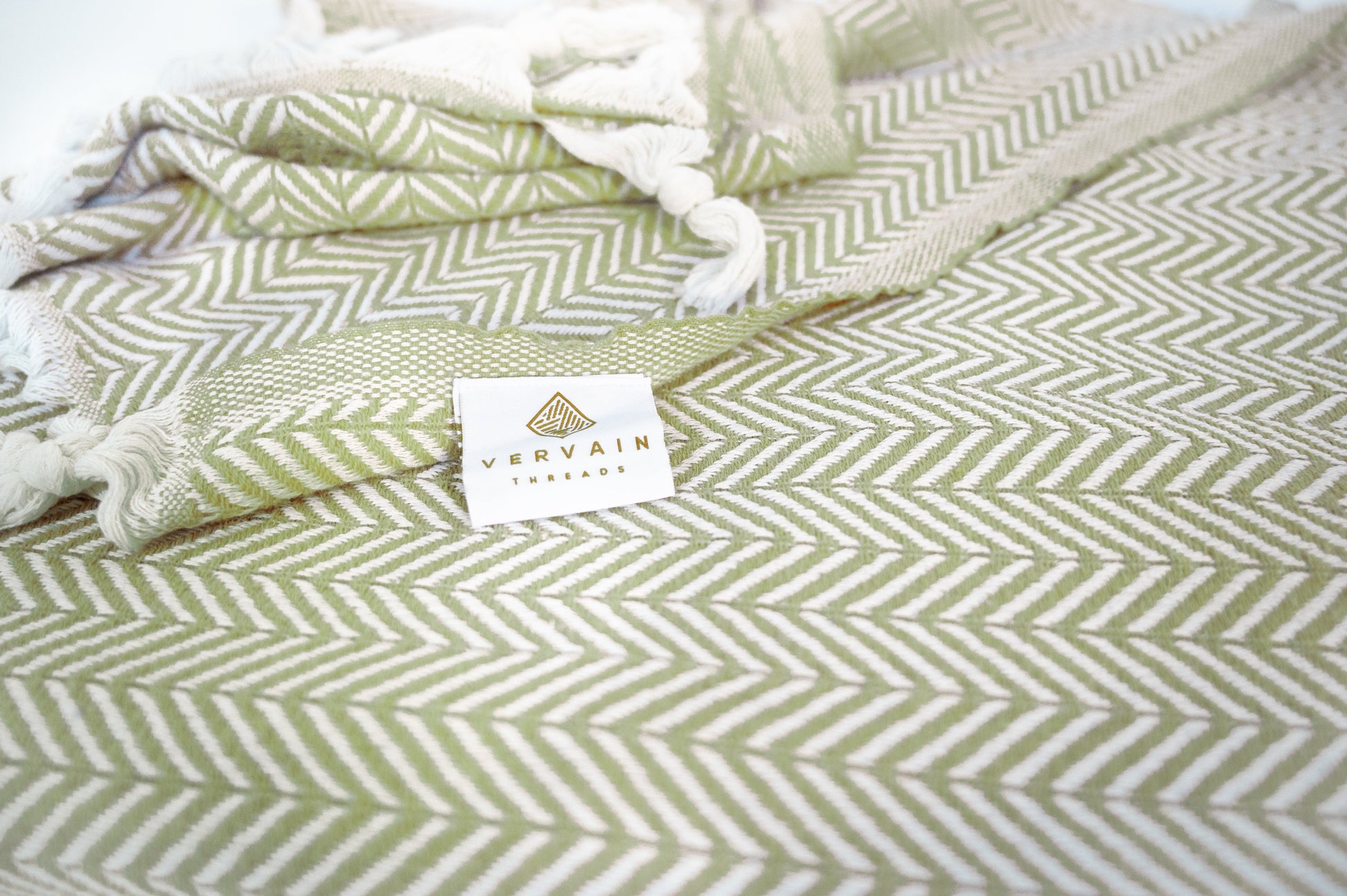 A close up shot of the palmetto green herringbone throw blanket with the detailed weave visible.