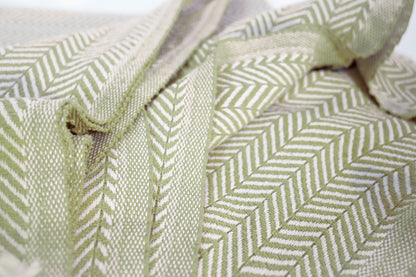 Another closeup shot of the cotton herringbone throw blanket with the palmetto green color displayed in detail.