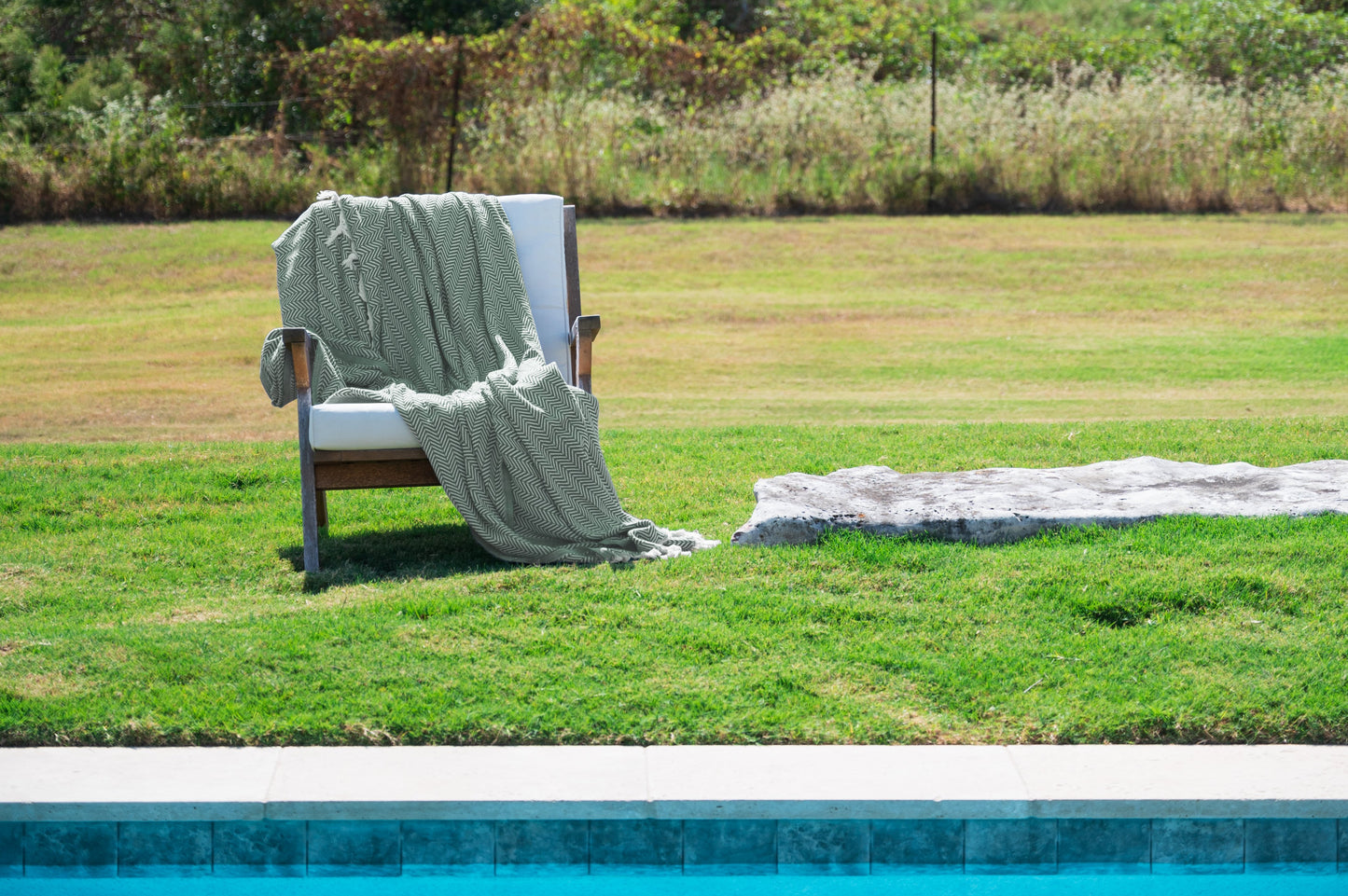 An image of the palmetto green throw blanket draped over a chair outside. 