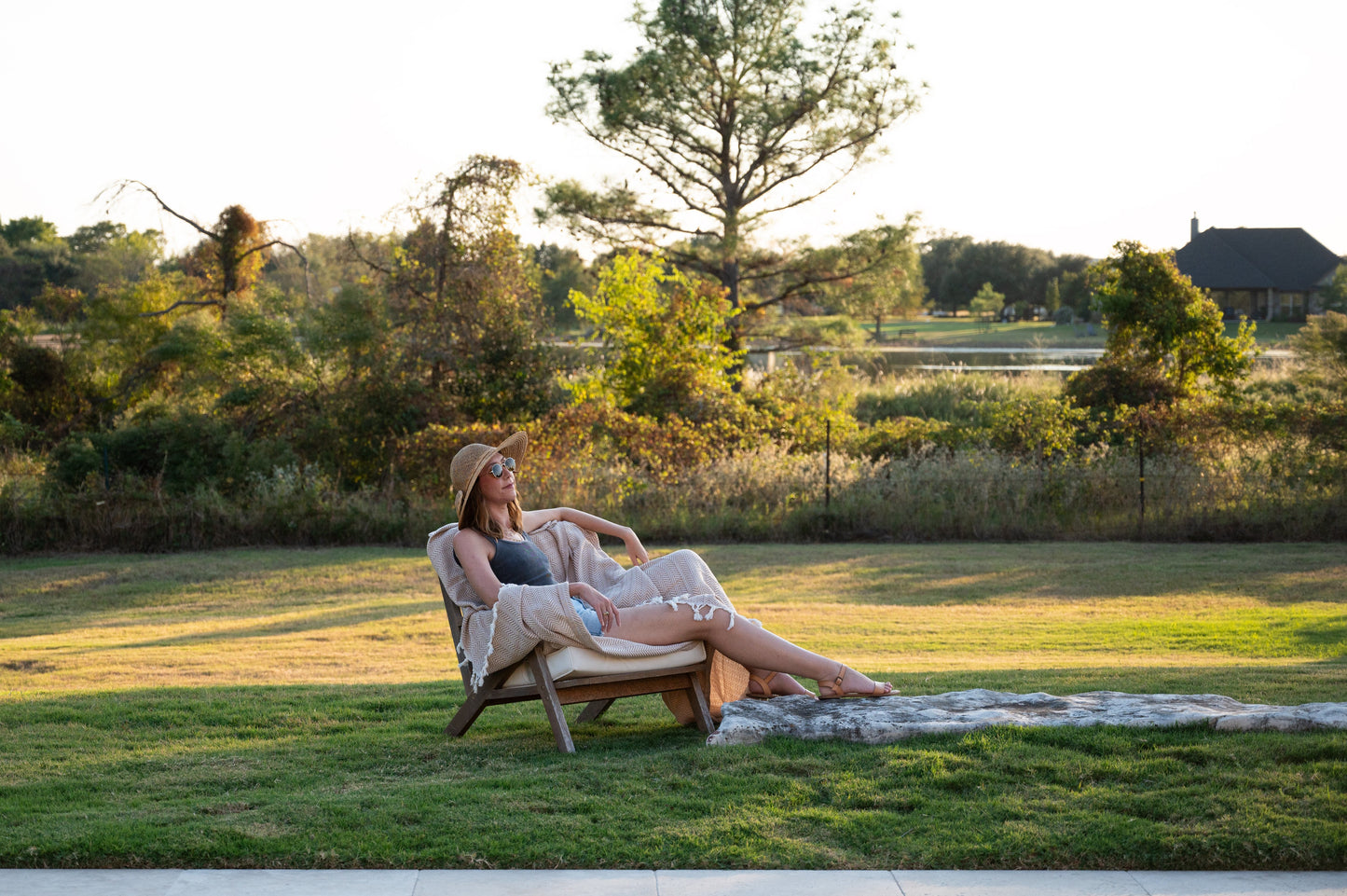 An image of a woman sitting relaxed on a chair with the desert stone herringbone throw blanket.