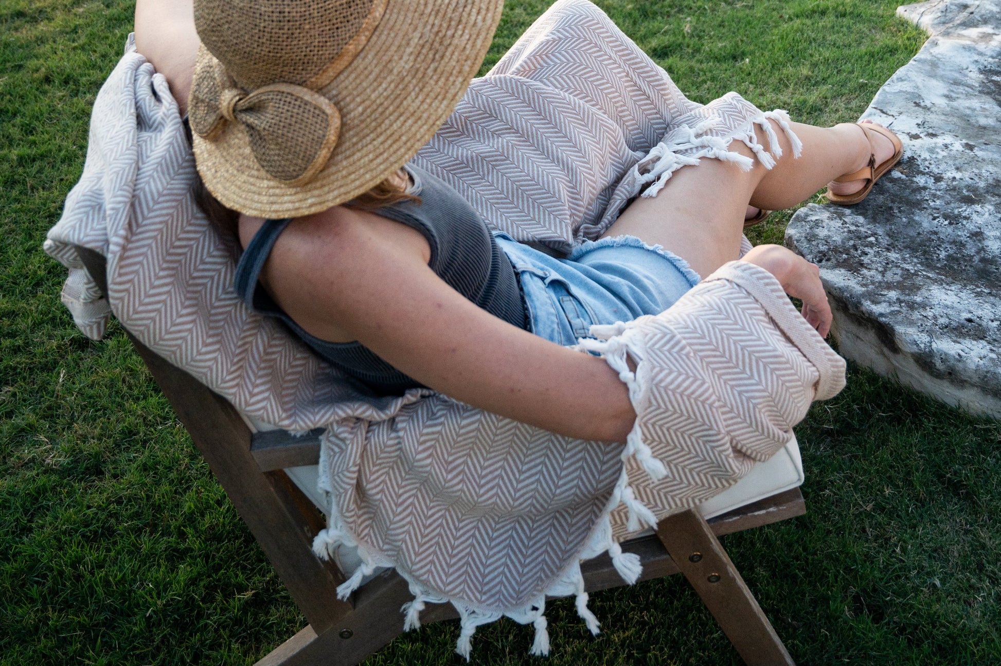 Another perspective of the woman sitting on the chair with the soft desert stone throw blanket.