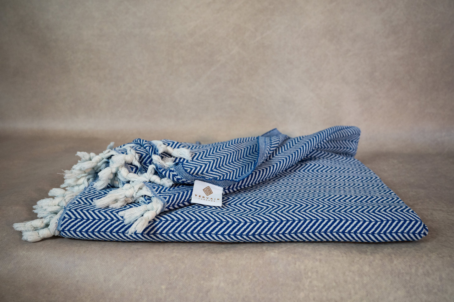 An image of the blue herringbone throw blanket with the beautiful herringbone weave visible as well as the hand-tied fringes.