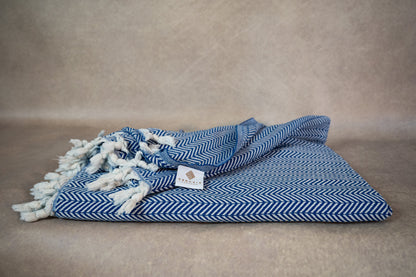 An image of the blue herringbone throw blanket with the beautiful herringbone weave visible as well as the hand-tied fringes.