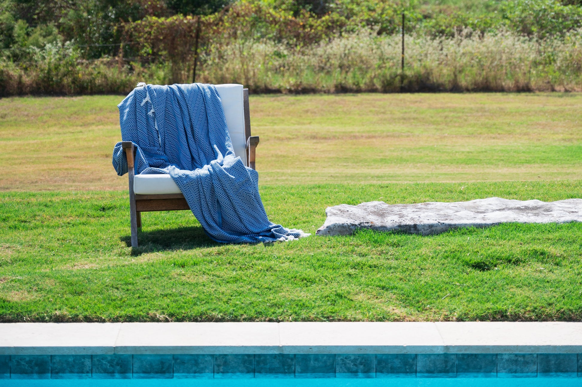 An image of the blue herringbone throw blanket draped over a chair outside.