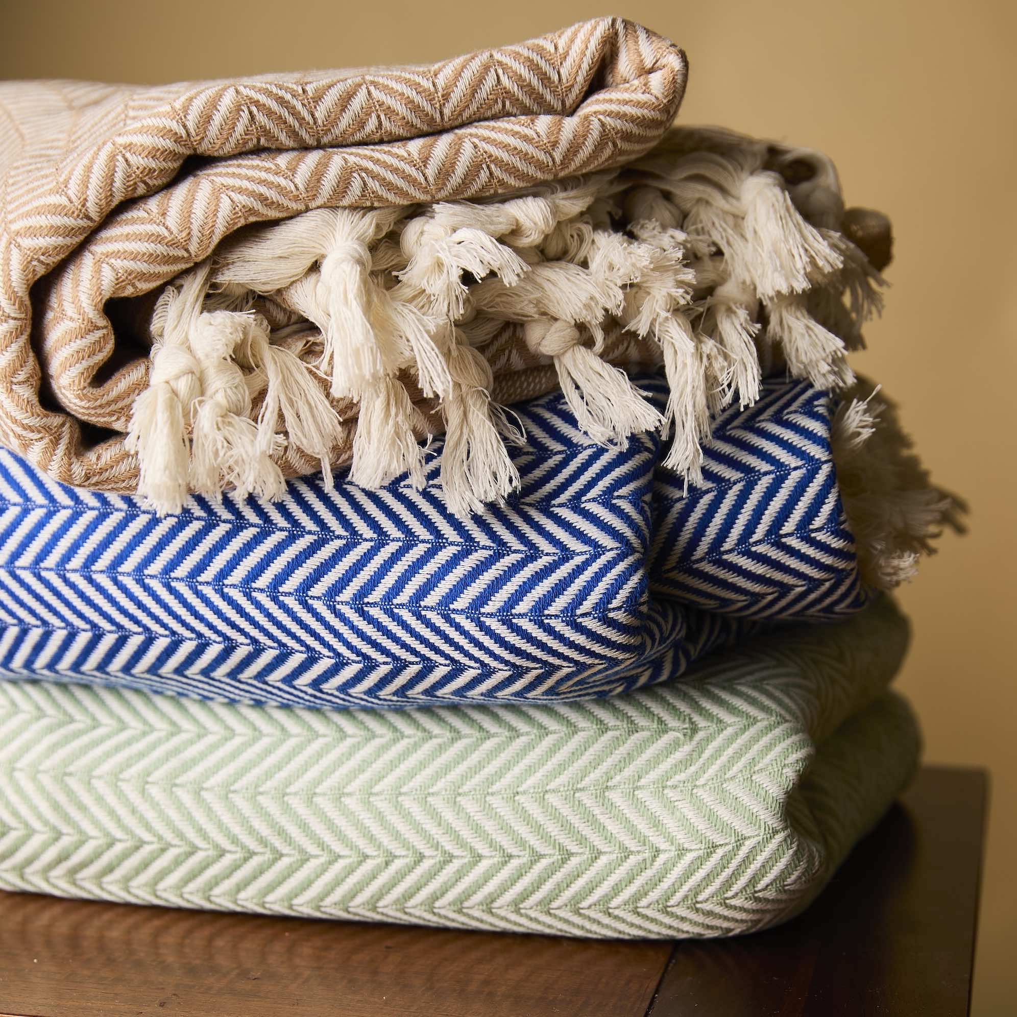 Ocean Blue, Desert Stone, and Palmetto Green herringbone throws stacked together